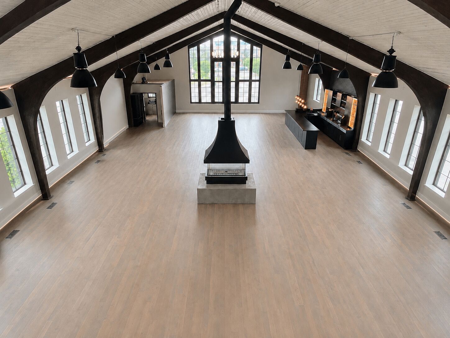 Open main floor of THE 1301 with vaulted ceilings, black beams, and suspended fireplace — a blank canvas for events in Saint Louis