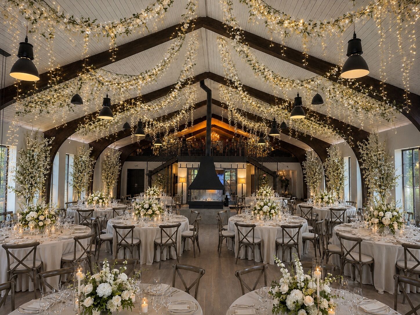 Wedding reception at THE 1301 with round tables beneath hanging floral garlands and the suspended fireplace